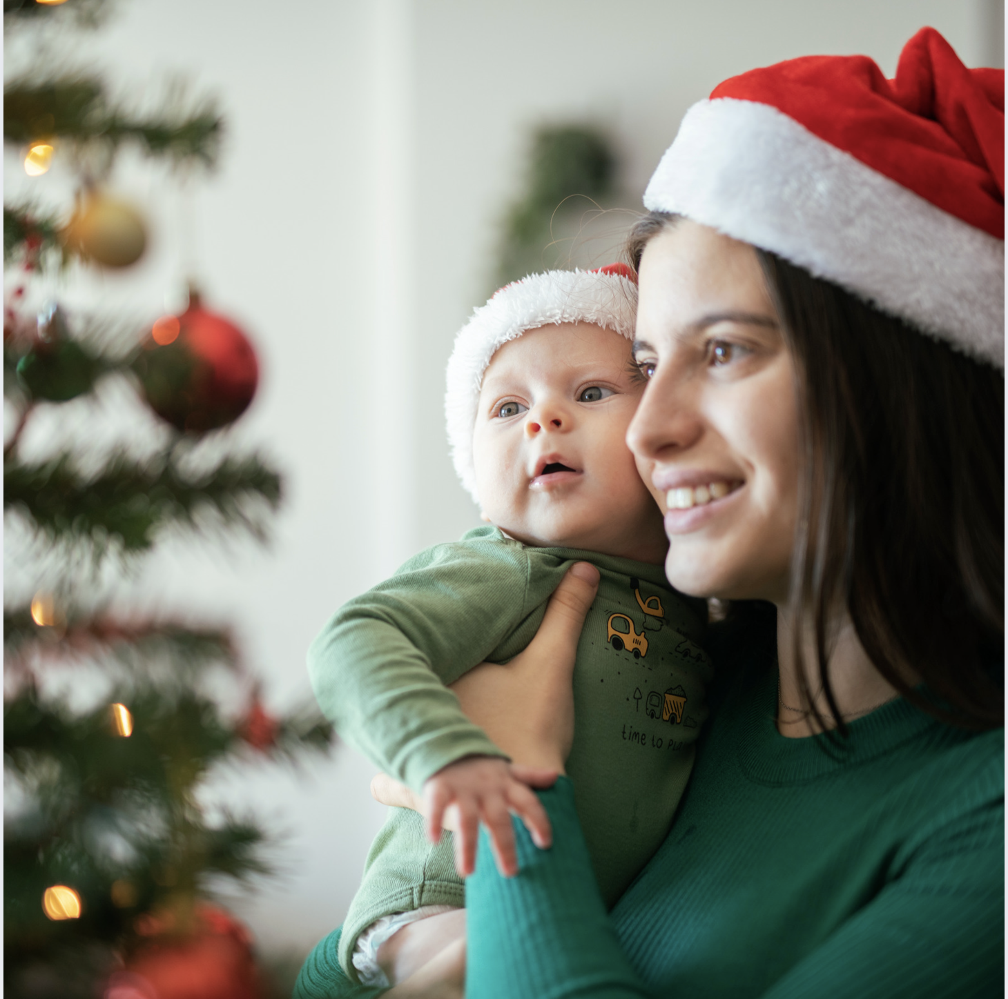 Woman holding a baby looking at a Christmas tree